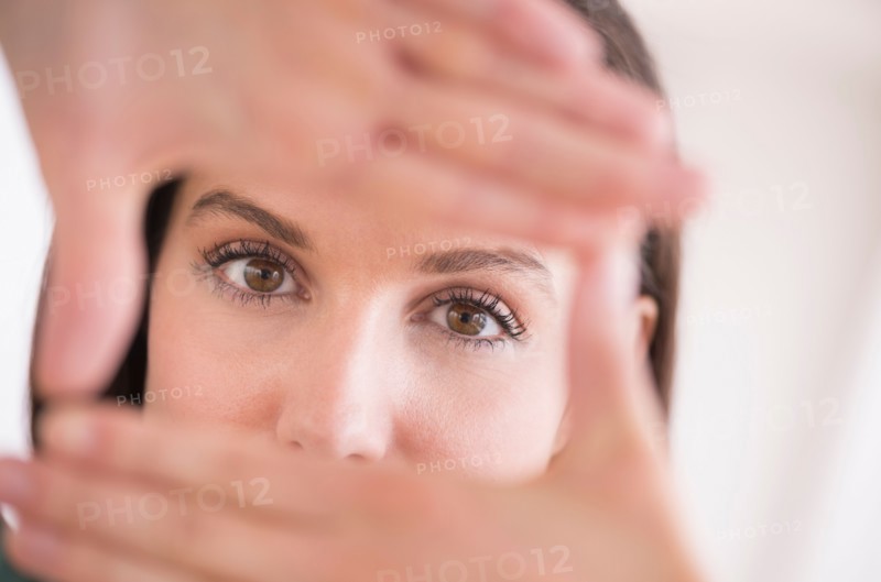Woman looking at camera through handsframe.