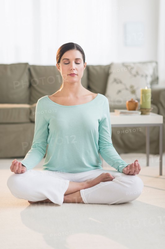 Woman meditating in living room.