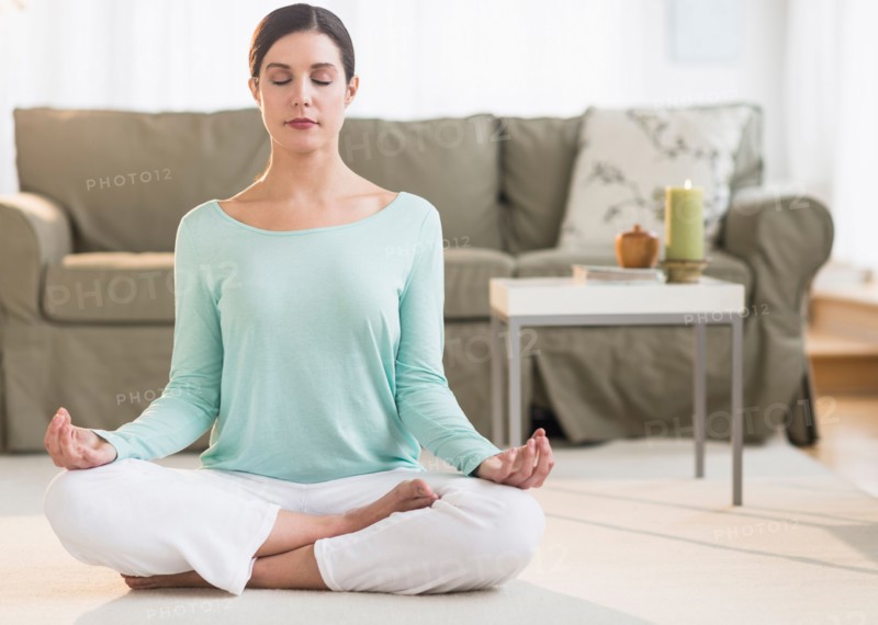 Woman meditating in living room.