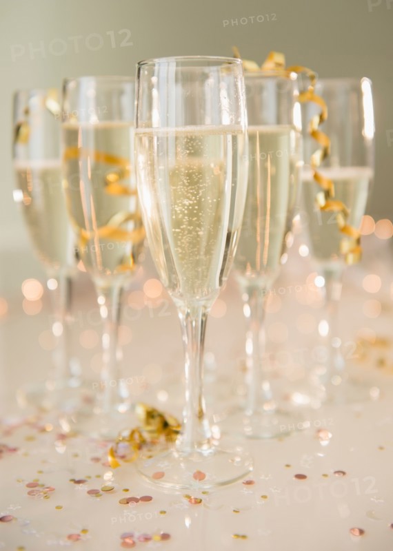 Champagne flutes on table decorated with confetti and streamer