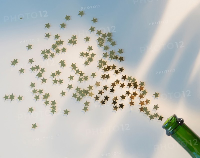 Star shape confetti splashing out of champagne bottle