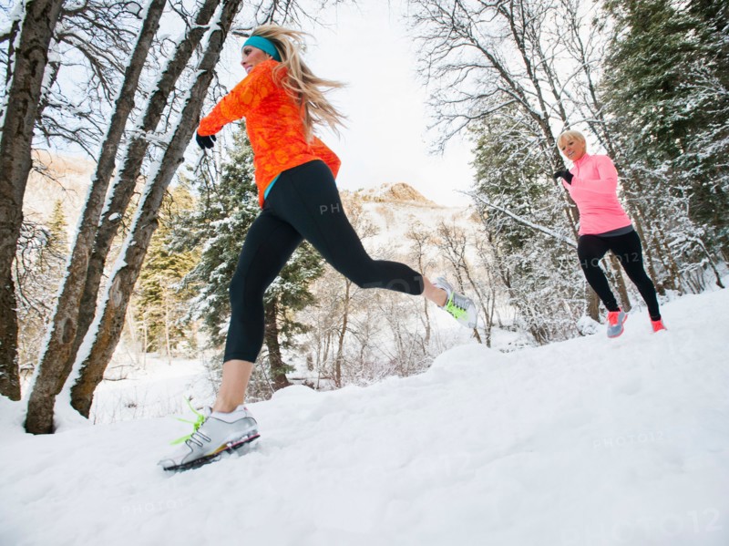 Two women jogging in winter forest