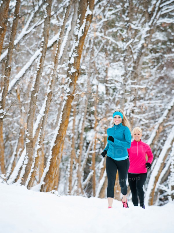 Two women jogging in winter forest