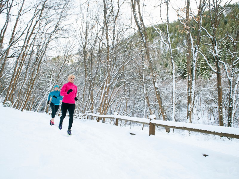 Two women jogging in winter forest