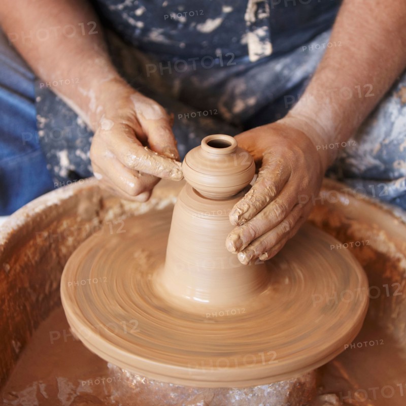 Elevated view of hands working with clay on potter's wheel