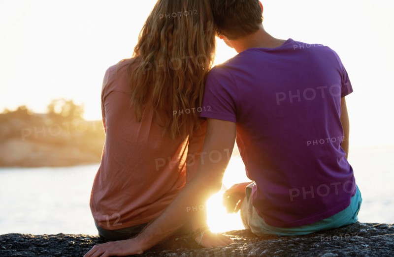 Rear view of young couple sitting at beach