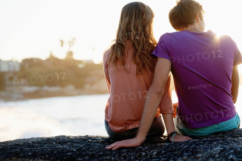 Rear view of young couple sitting at beach