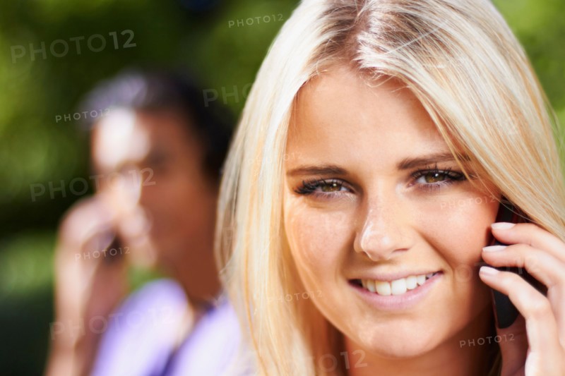 Portrait of young woman on phone, man in background