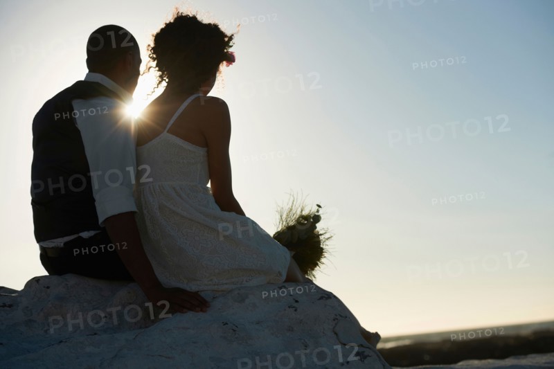 Newlywed couple looking at setting sun