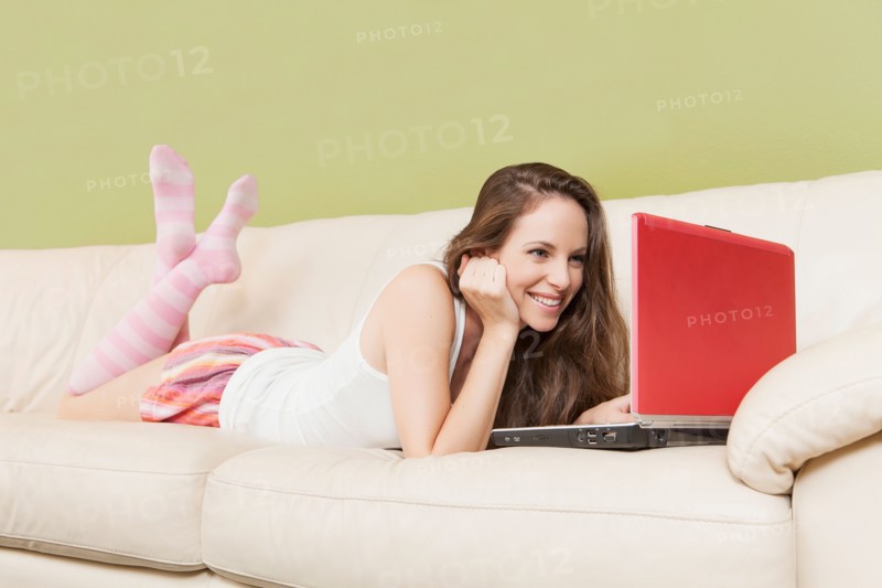 Woman lying on sofa with laptop