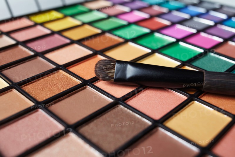 Make-up brush on eye shadow palette, studio shot