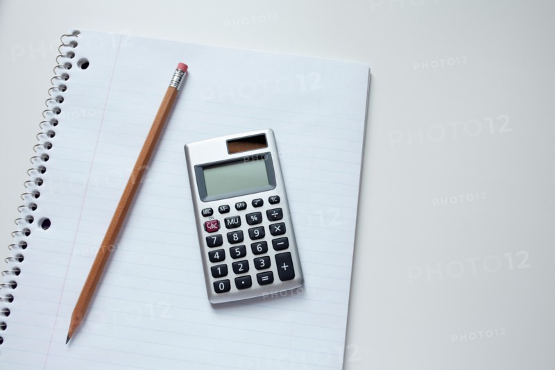 Calculator and pencil on notepad, studio shot