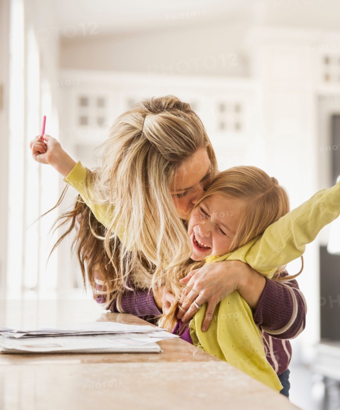 Mother kissing daughter (6-7) during doing homework