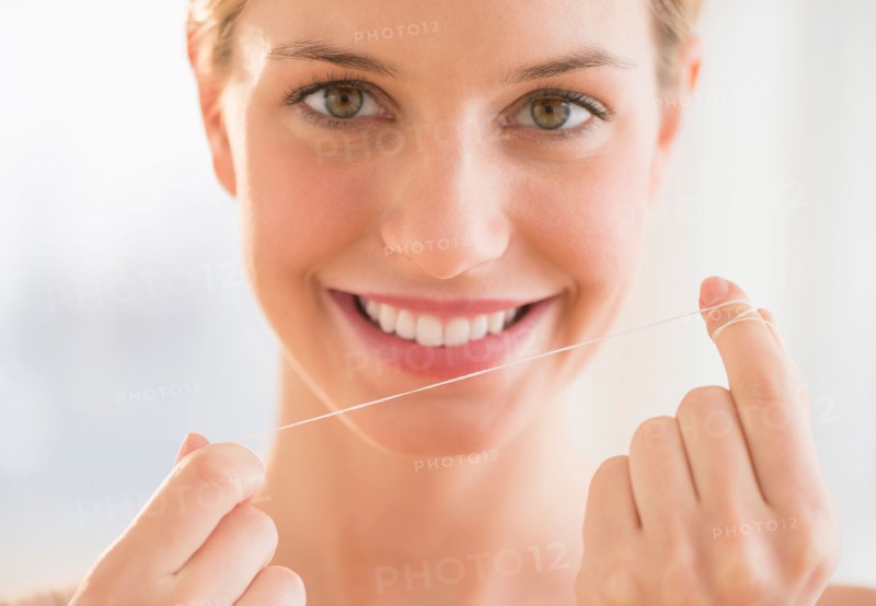 Portrait of woman flossing teeth.