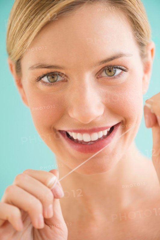 Portrait of woman flossing teeth.