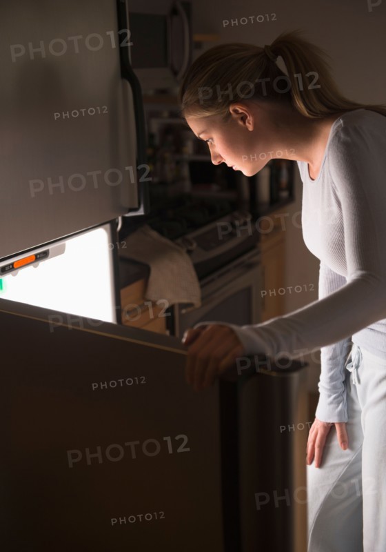Woman opening fridge at night.