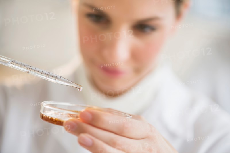 Close-up of scientist using pipette and petri dish.
