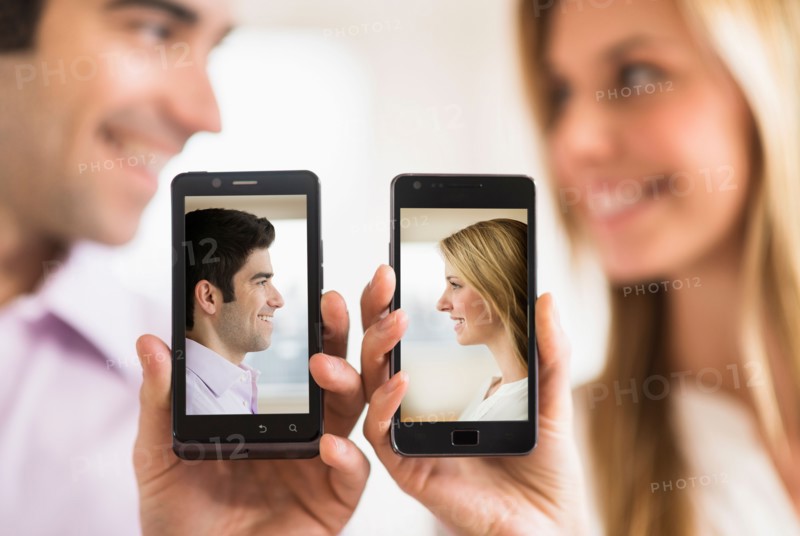 Couple holding smartphones with their pictures on.