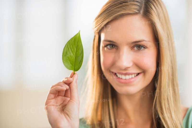 Portrait of woman holding leaf.