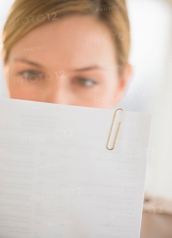 Close-up of young woman reading documents.