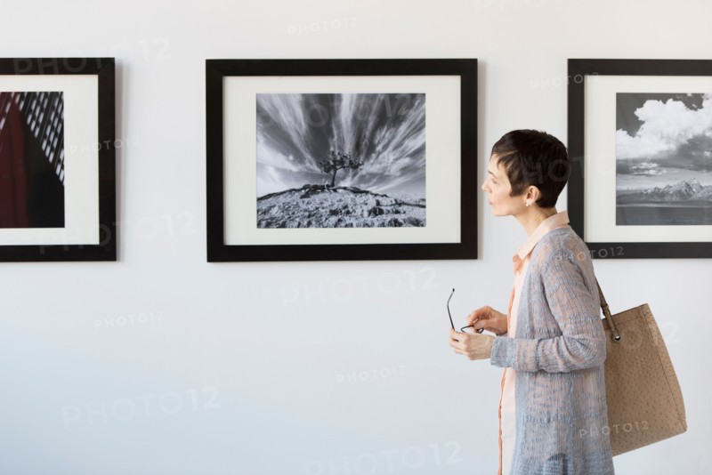 Woman watching photographs in art gallery.