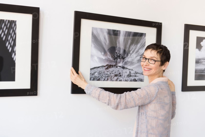 Woman hanging photographs in art gallery.