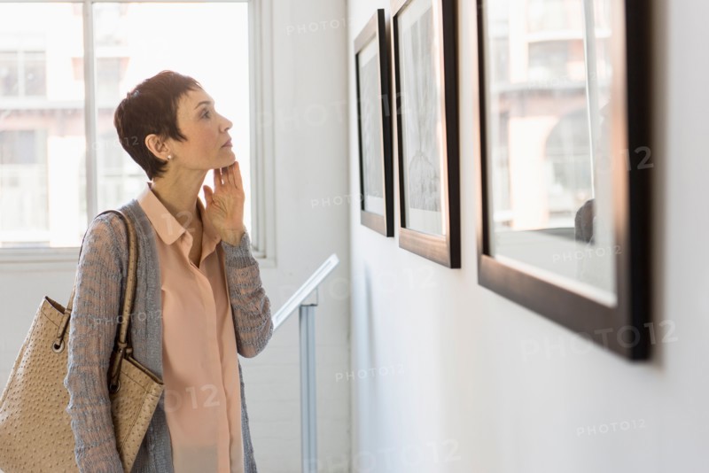 Woman watching photographs in art gallery.