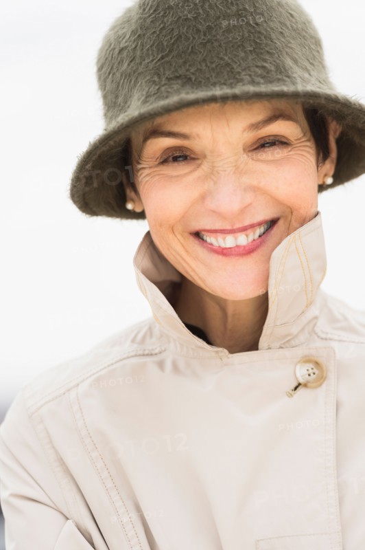 Portrait of smiling woman wearing raincoat and hat.