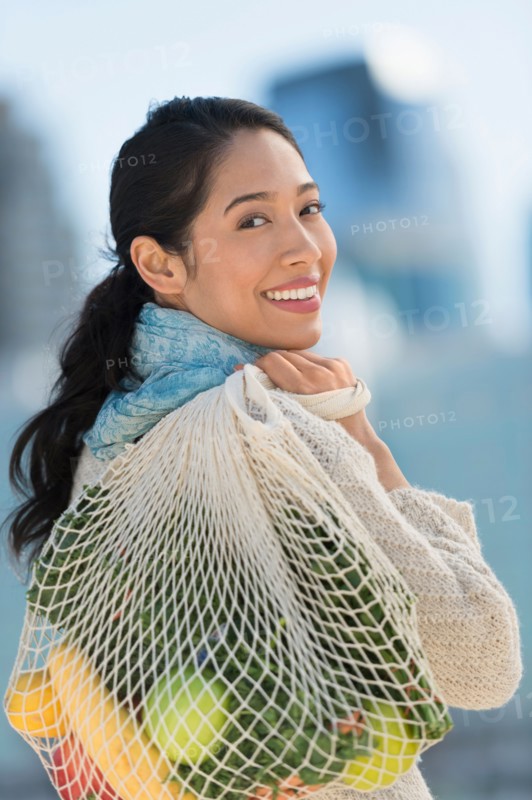 Portrait of smiling young woman with grocery shopping bag.