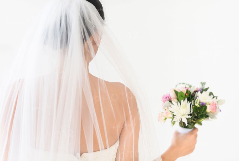Portrait of bride in veil holding bouquet.