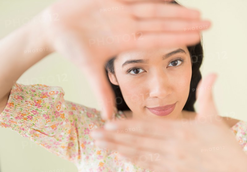 Young woman looking through hand frame.