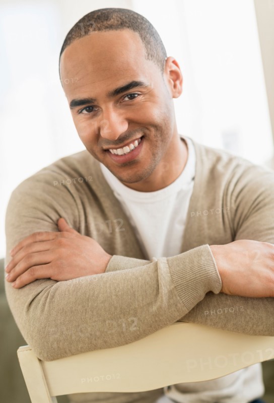 Portrait of young man sitting with arms crossed.