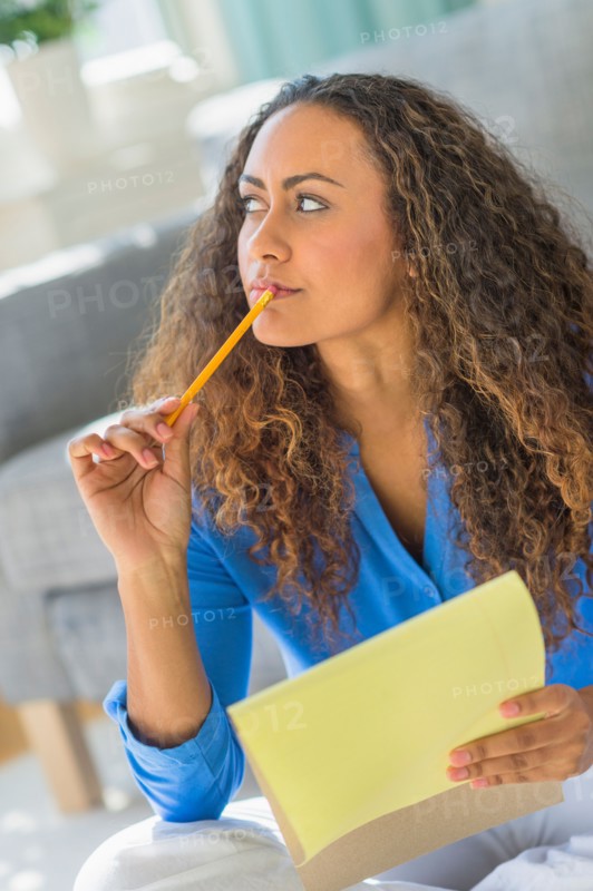 Young woman writing in yellow notepad.