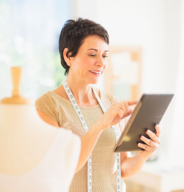 Portrait of mature woman with clothing bust using digital tablet