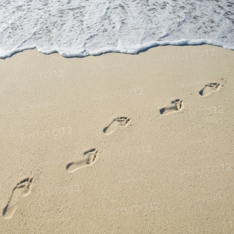 Footprints on Sandy Beach leading into sea