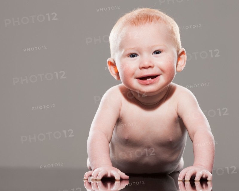 Studio shot of naked baby boy (18-23 months) crawling