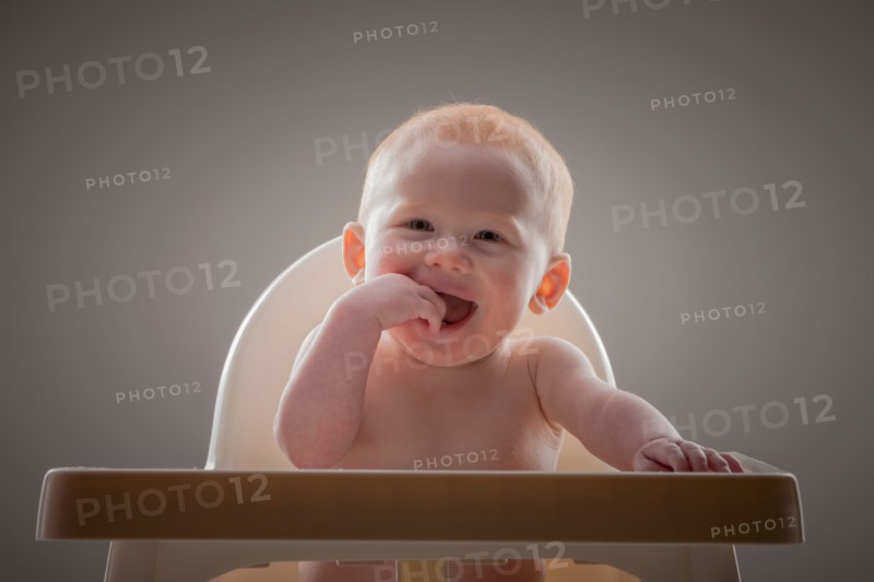Studio shot portrait of naked baby boy (18-23 months) with finger in mouth