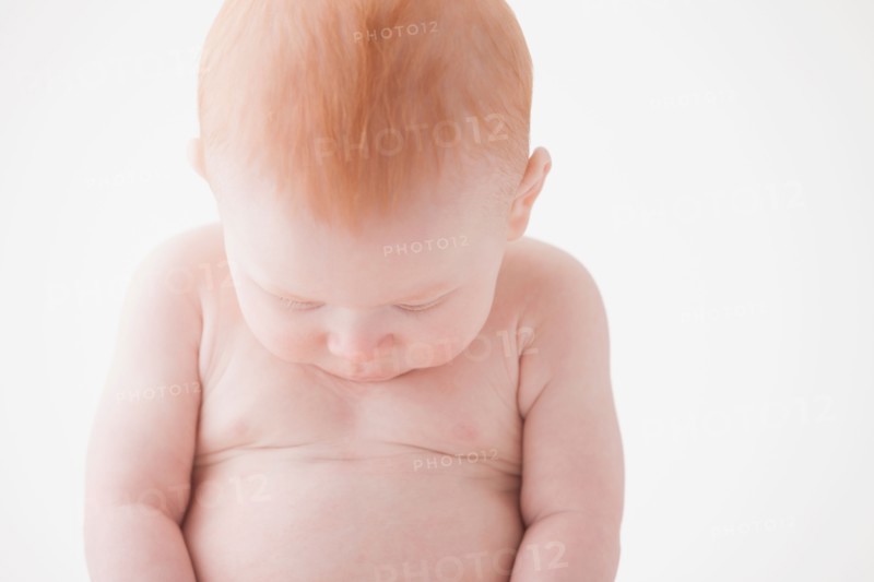 Naked baby boy (18-23 months) looking at his belly