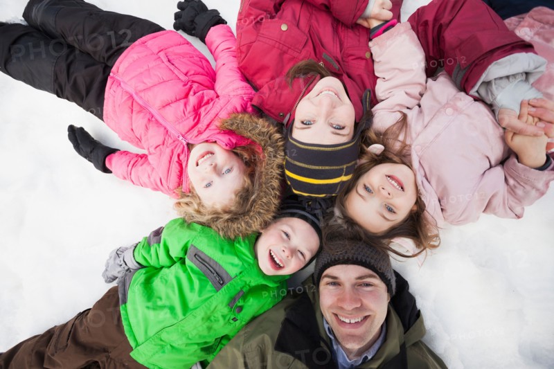 Directly above portrait of three children (2-3, 4-5) with parents lying on snow
