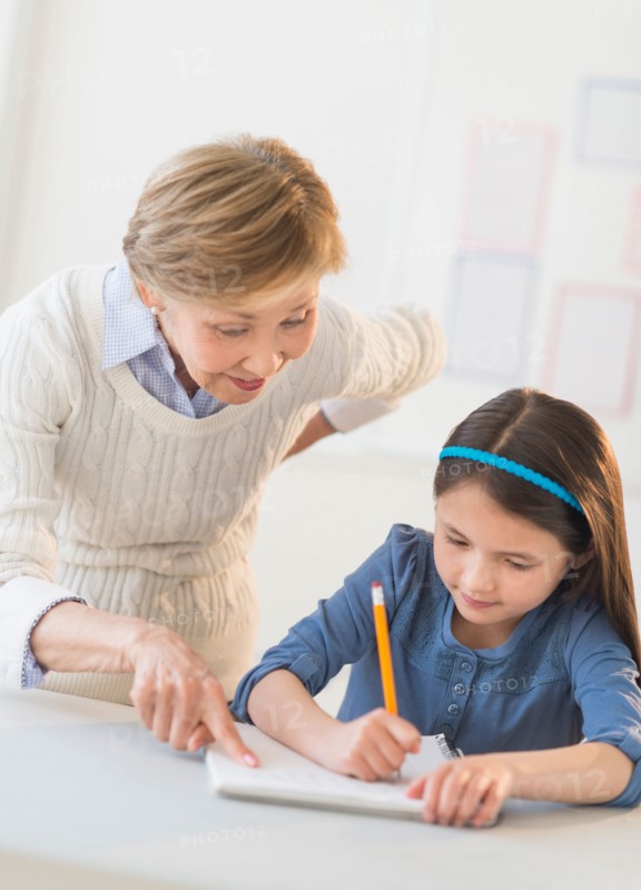 Teacher helping schoolgirl (8-9) at school.