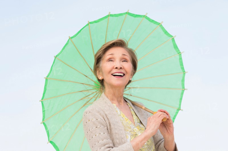 Portrait of senior woman holding green parasol.