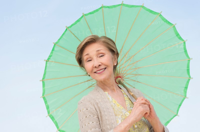 Portrait of senior woman holding green parasol.
