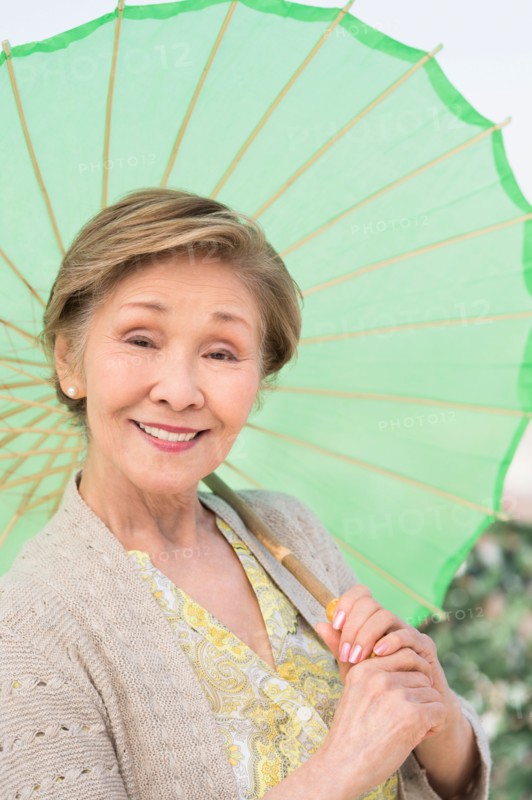 Portrait of senior woman holding green parasol.