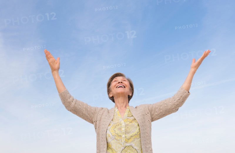 Senior woman looking up at blue sky.