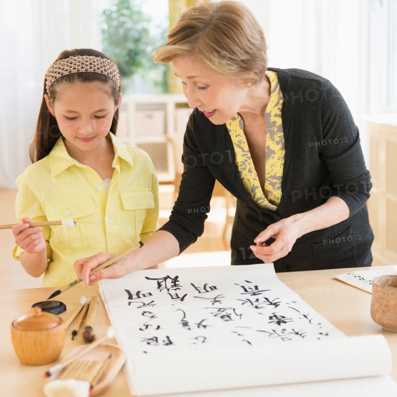 Grandmother and granddaughter (8-9) painting japanese symbols.