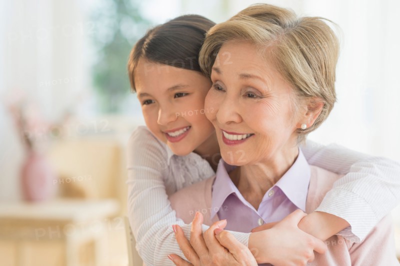 Granddaughter (8-9) embracing grandmother.