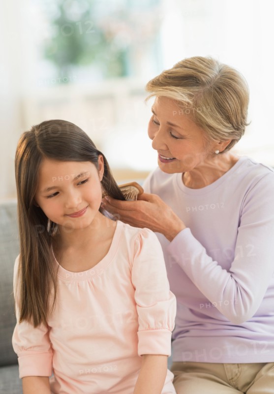 Grandmother brushing granddaughter's (8-9) hair.