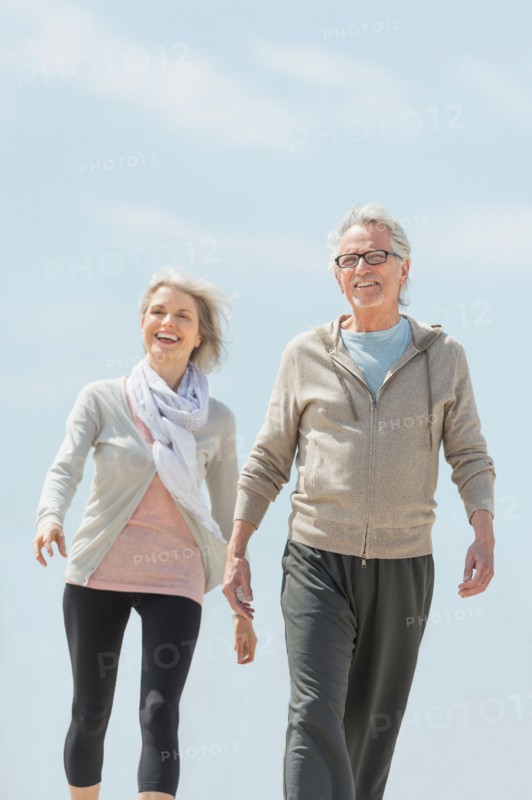 Senior couple walking and holding hands.