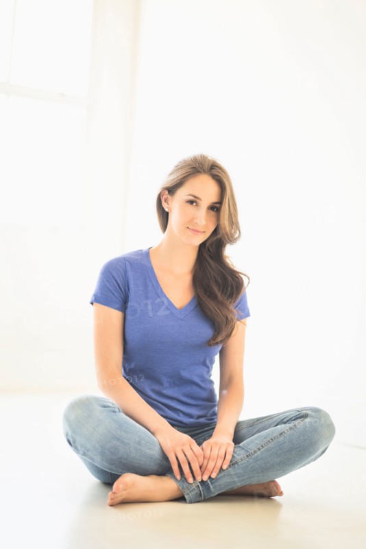 Portrait of young woman sitting on floor.