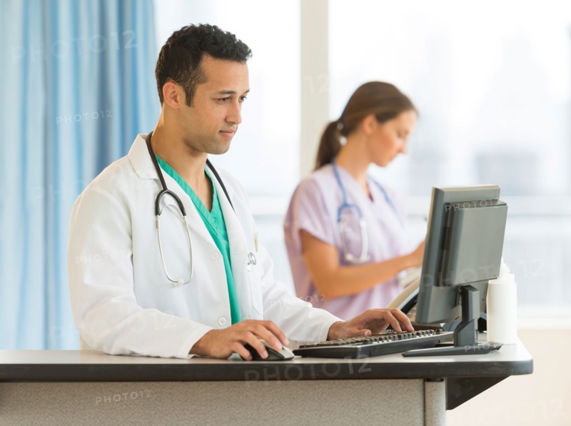 Male and female nurses working at nurse's station in hospital.
